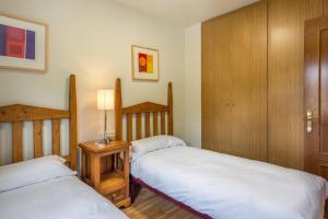 1 dormitorio con 2 camas y mesa con lámpara en PIRENNE, en Vielha