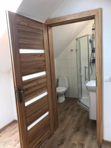 a bathroom with a toilet and a wooden door at Apartament Mazurski Rodowo in Sorkwity