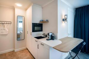 a small white kitchen with a counter and a sink at Hotel Villa Vida in Domburg