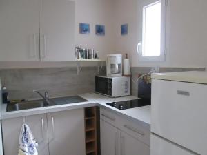 Una cocina blanca con fregadero y microondas. en A 350m de la plage, en Fouesnant