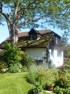 a house with a grass roof and a tree at Strawberry Cottage B&B in Hedge End