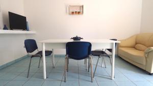 una mesa y sillas en una sala de estar con sofá en Le Villette di Torre Suda by Salento Affitti, en Torre Suda