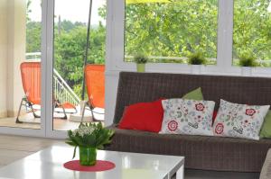uma sala de estar com um sofá com almofadas num alpendre em Słoneczna Villa em Mrągowo
