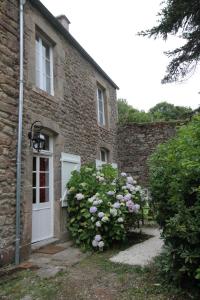 ein Backsteinhaus mit einer weißen Tür und ein paar Blumen in der Unterkunft Le Presbytère, Cotentin, Val de Saire, Fermanville, proximité immédiate mer et forêt in Fermanville