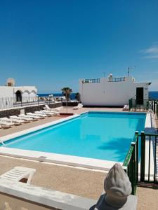 a swimming pool with chairs and the ocean in the background at MI ALMA in Puerto del Carmen