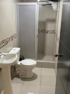 a bathroom with a shower and a toilet and a sink at GIGAHOUSE in Baños