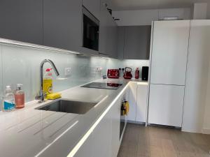 a white kitchen with a sink and a refrigerator at Modern & Spacious Penthouse in North London in London