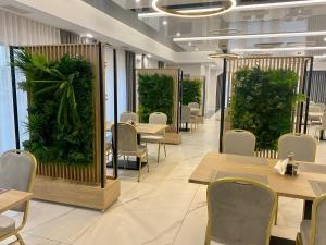 a restaurant with tables and chairs and plants at Hotel Sebory in Przasnysz
