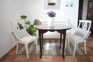 einen Tisch mit zwei Stühlen und eine Vase mit Blumen darauf in der Unterkunft Casa SocAire. Naturaleza, mar, paz, relax. in Tabayesco