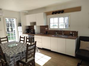 a kitchen with white cabinets and a table and a dining room at Ty gwenn in Cancale