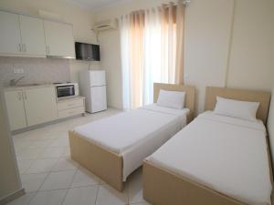 two beds in a small room with a kitchen at Sunset Apartments Berdenesh Sarandë in Sarandë