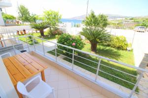 a balcony with a wooden bench and a view of the water at Sunset Apartments Berdenesh Sarandë in Sarandë