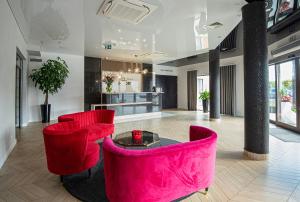 a lobby with two red chairs and a table at Hotel Sebory in Przasnysz