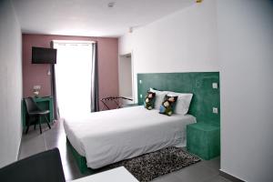 a bedroom with a large bed with a green headboard at Ammaia AL in Portalegre