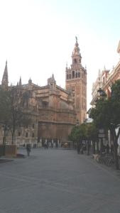 un gran edificio con una torre de reloj en una ciudad en Apartamentos Quintero, en Sevilla