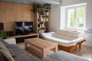 ein Wohnzimmer mit einem Sofa und einem TV in der Unterkunft Belle maison familiale dans la campagne Bretonne in La Croix-Helléan