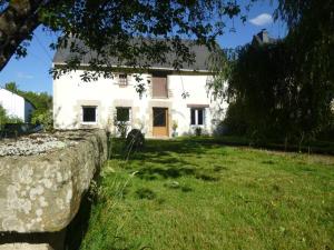 ein weißes Haus mit einer Steinmauer davor in der Unterkunft Belle maison familiale dans la campagne Bretonne in La Croix-Helléan