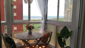 a table and two chairs in a balcony with windows at Espectacular apartment con piscina, vistas al mar y tranquilidad 10 min desde Valencia in Puebla de Farnals