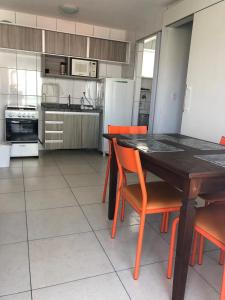 a kitchen with a wooden table and orange chairs at Studio Iracema Temporada Aconchegante in Fortaleza