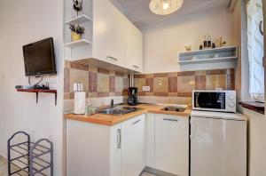 - une petite cuisine avec des placards blancs et un four micro-ondes dans l'établissement Lovely Apartments in Valbandon, à Fažana