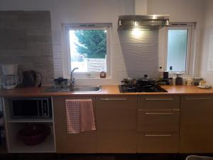 een keuken met een wastafel, een fornuis en een raam bij - La Maison des Bois - in Les Bréviaires