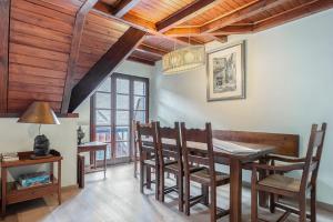 a dining room with wooden ceilings and a table and chairs at Luderna - Tríplex Nin C2 Arenho in Naut Aran +12 photos
