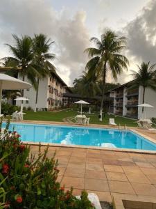 a swimming pool in front of a building with palm trees at Casa Sol e Mar Beira-mar in Ilhéus