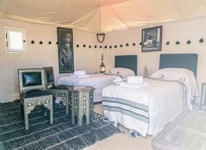 a room with three beds and a chair at Erg Lihoudi Luxury desert camp with Camel ride, meals & sandboarding in Boumalne