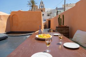 uma mesa de madeira com uma taça de frutas e copos de vinho em Azalea Houses em Oia