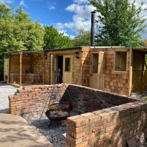 a building with a brick wall and a grill at Bee Bole Cabin in Monmouth