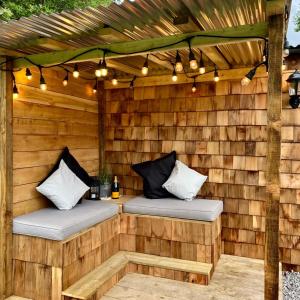 a wooden pergola with two beds and lights at Bee Bole Cabin in Monmouth