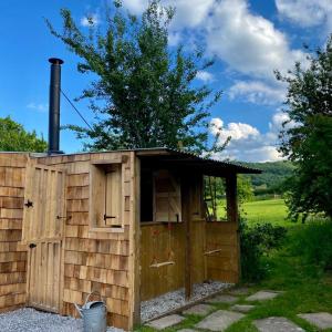 a wooden out house with a chimney and a bucket at Bee Bole Cabin in Monmouth