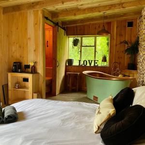 1 dormitorio con cama y bañera en Bee Bole Cabin en Monmouth