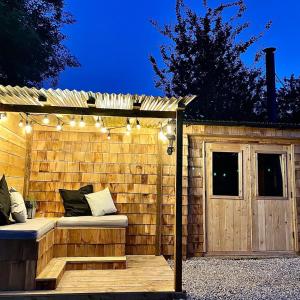 a wooden pergola with a bench and lights at Bee Bole Cabin in Monmouth