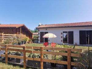 una casa con una valla y un paraguas en un patio en Gîte entre lacs, océan et forêts, en Pissos