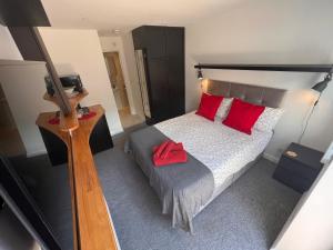a bedroom with a large bed with red pillows at Larmins Room in Milton Keynes