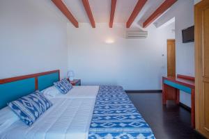a bedroom with a large bed with blue pillows at Castell de Lô in Cala'n Porter