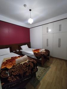 um quarto de hotel com duas camas e uma parede vermelha em E-Just Hotel Borg El Arab em Borg El Arab