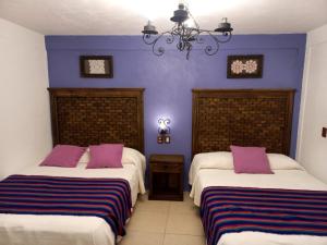 2 camas en una habitación con paredes moradas en La Escondida Hotel Boutique en Zacatlán