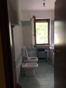 baño con aseo y lavabo y ventana en Casa vacanze pila, en Charvensod