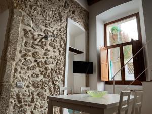 a dining room with a table and a stone wall at La Rupe Apartments Tropea in Tropea