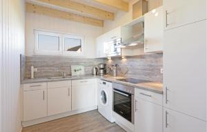 オルペニッツにあるAwesome Home In Ostseeresort Olpenitz With Kitchenのキッチン(白いキャビネット、洗濯機、乾燥機付)