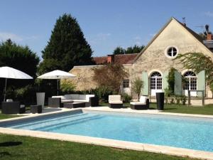 a pool with chairs and umbrellas in front of a house at Le Clos des Aubrys in Châteauroux