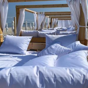 a row of white beds with white sheets and pillows at Wave Resort & Spa Magic Apartaments with sea view in Międzyzdroje
