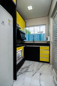 uma cozinha com armários amarelos e pretos e um lavatório em Sobrado Smart - Melhor Localização de Foz do Iguaçu em Foz do Iguaçu