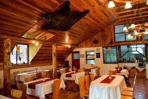 un ristorante con tavoli, sedie e soffitti in legno di Vila Maria Bran a Şimon