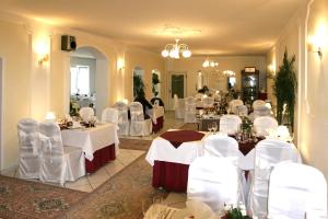un salón de banquetes con mesas blancas y sillas blancas en Penzion Romantik, en Dolná Streda