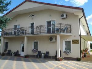 a large white building with a balcony and chairs at Penzion Romantik in Dolná Streda