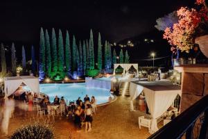 un groupe de personnes assises autour d'une piscine la nuit dans l'établissement Ai Pozzi di Lenola, à Lenola