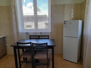eine Küche mit einem Tisch, einem Kühlschrank und einem Fenster in der Unterkunft Melkonyan's home in Gjumri